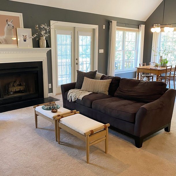 A bright living room with a brown sofa, ottomans and French doors, staged for sale
